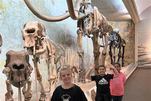 Smiling Wasmer students in front of fossil displays at a museum